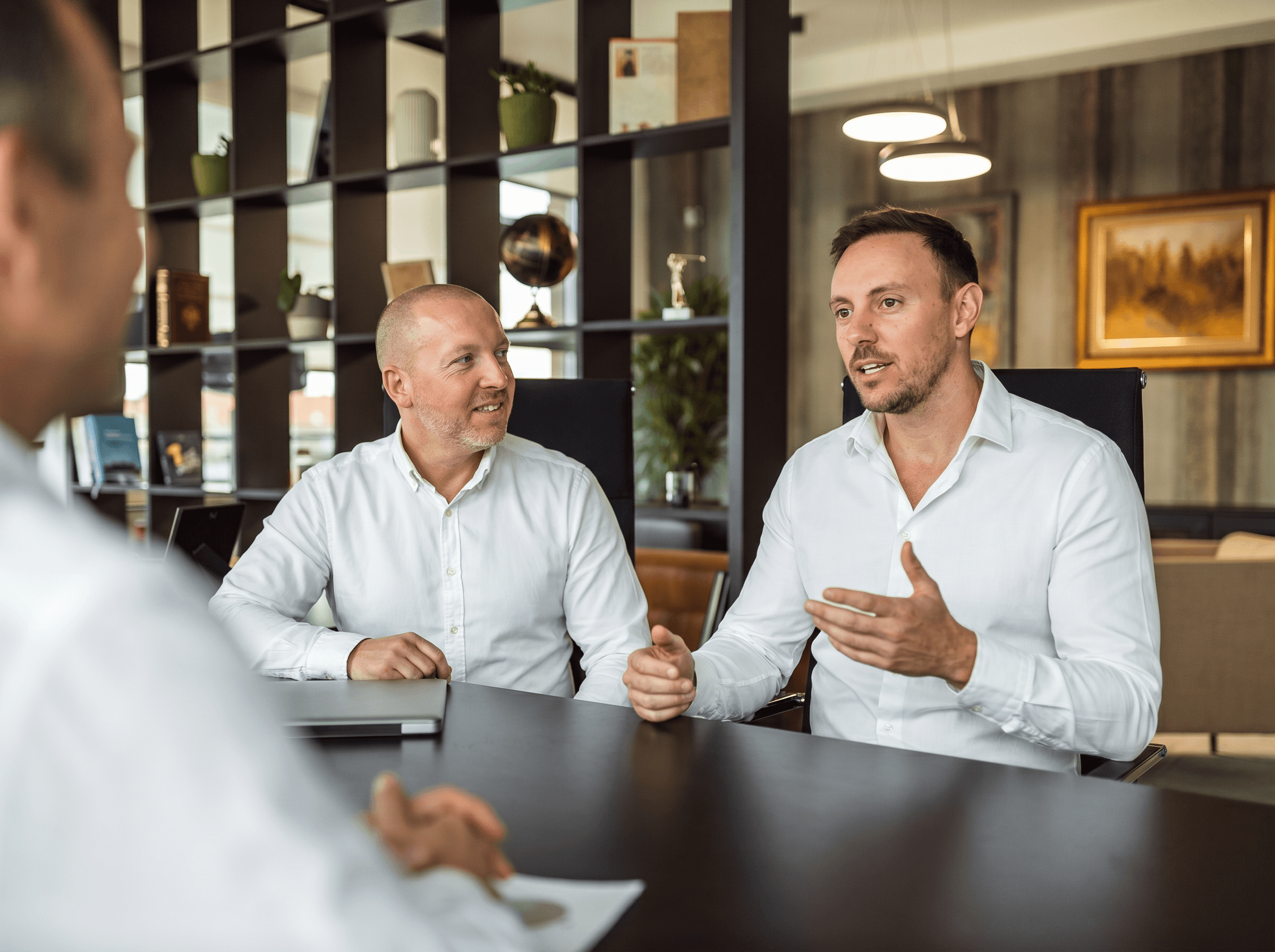 Two colleagues in conversation across a desk.