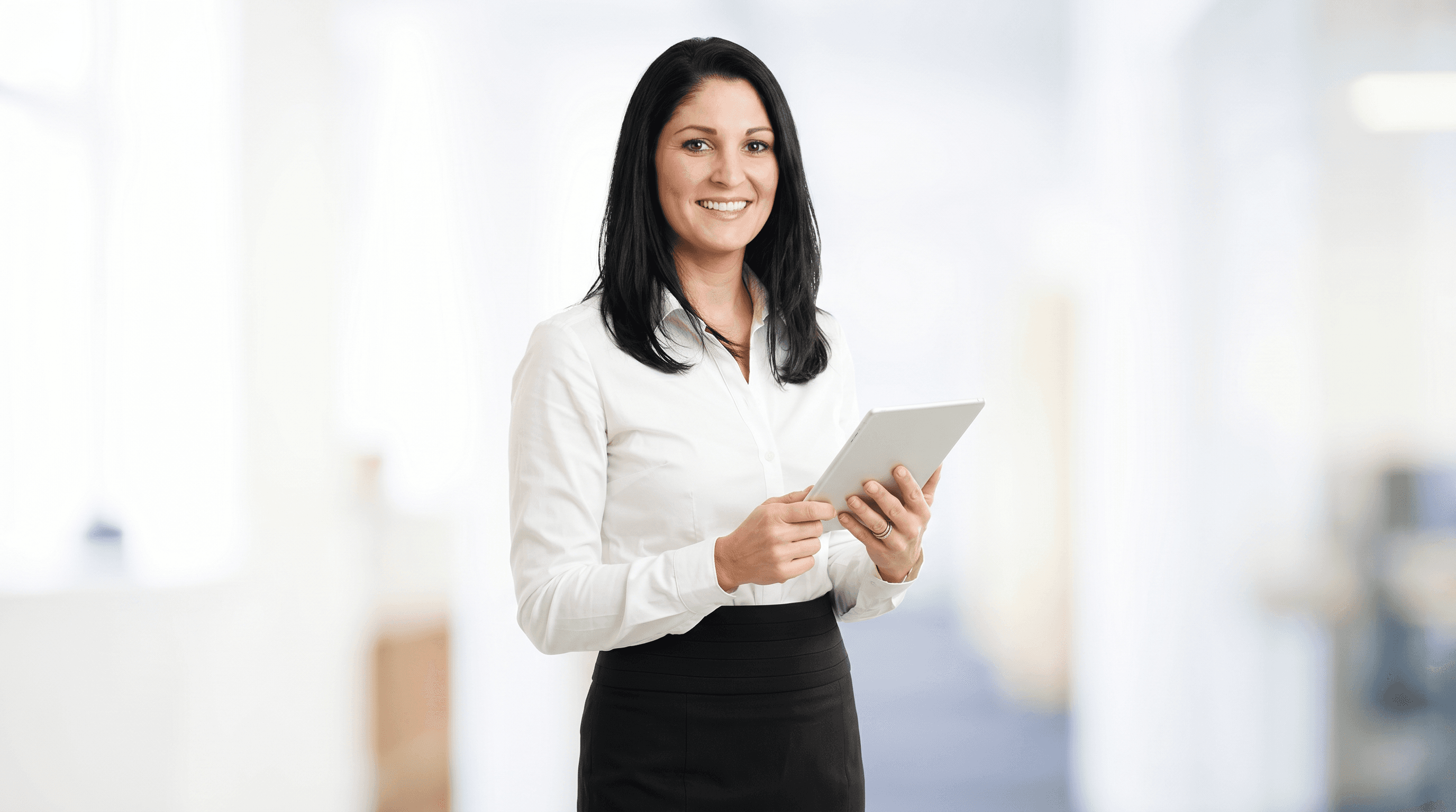 A colleague holding a tablet in a bright interior.